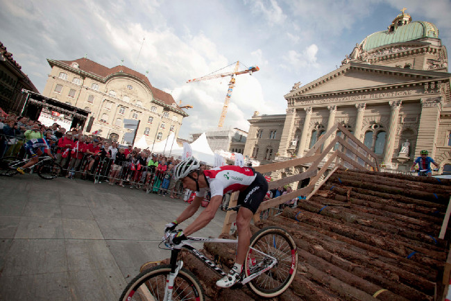 Nino Schurter, vlevo prchající Julie Bresset, nahoře stíhající Ondřej Cink